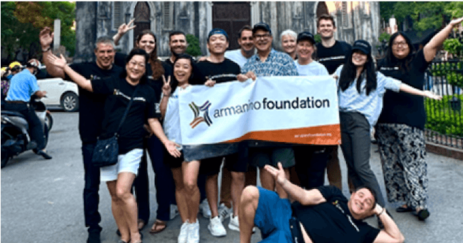 Exterior group shot of Armanino Foundation members cheering and holding an Armanino banner.